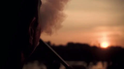 Young guy smokes a hookah on a sunset background Stock Footage 160757005