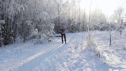 Young guy in the snow-covered forest playing the guitar Stock Footage 85291539