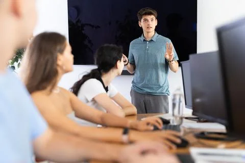 Young guy speaker stands in front of students and talks about use of artificial Stock Photos