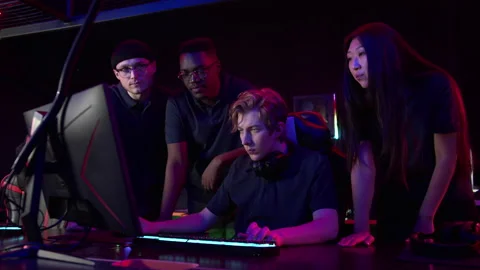 A young guy spends a tense match in a computer game, loses, gets upset, friends Stock Footage 152800898
