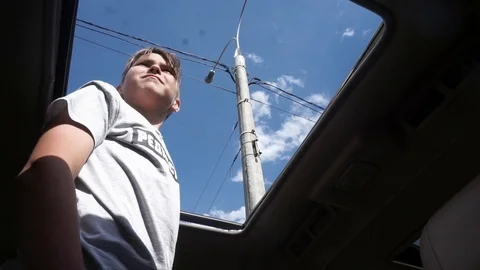Young guy stand in the car and sticking out of the hatch Video stock 102248739