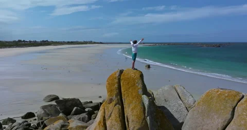 Young guy standing on huge stones on the shore of the Atlantic Ocean on the Stock Footage 293137411