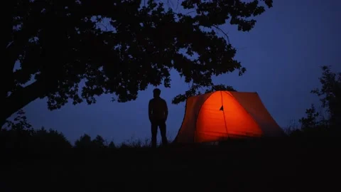A young guy standing near tree and looking behind camping tent. Time lapse Stock Footage 151117089