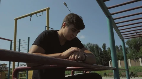 A young guy standing on the Playground controls the pulse of a smart watch on Stock Footage 109166091