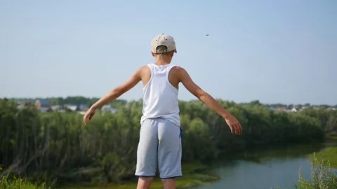 A young guy is standing on the river bank. Beautiful summer landscape Vidéo 78981827