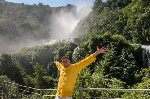 A young guy stands on the background of a waterfall Cascata delle Marmore in Ita Stock Photos