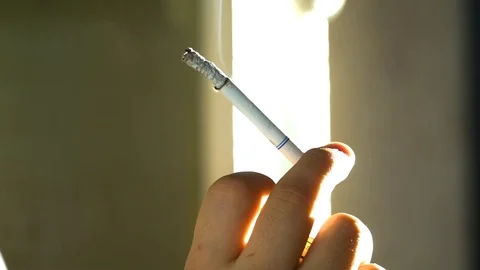 A young guy stands outside at night, in the city, in the autumn and smokes in an Stock Footage 86044812