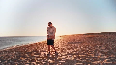 Young guy starts dancing trendy dance on the beach by the sea. Stock Footage 196714073