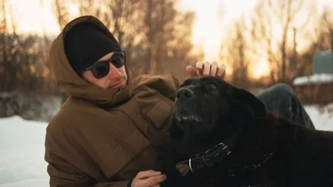 A young guy is stroking his dog. On open air. Winer. Vídeos de archivo 150331572