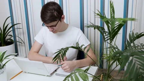 A young guy, a student with glasses, while studying onaline from home Stock Footage 169862348