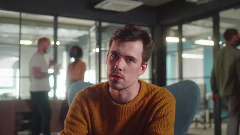 A young guy-student is sitting on the chair in the university and speaking to Stock Footage 175503057