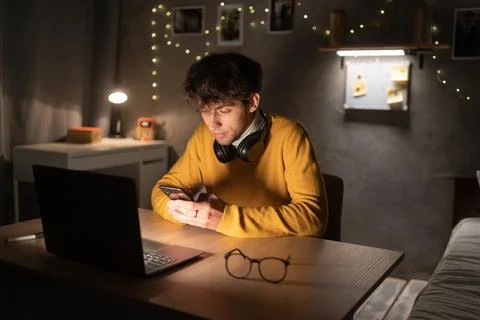 Young guy student studying at the college dormitory, sitting at the desk, u.. Stock Photos