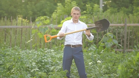 A young guy in a suit is dancing with a shovel in his hands. Stock Footage 93930950
