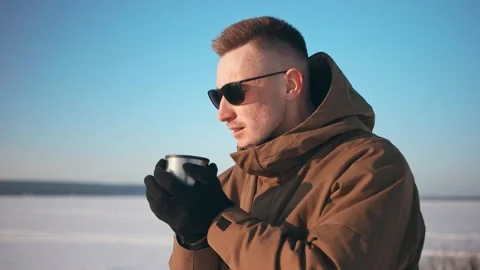 Young guy in sunglasses drinks tea from a thermos. Outdoors. Vídeos de archivo 150331208