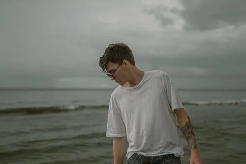 Young guy in sunglasses looking down at the sea 写真素材