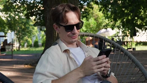 Young guy in sunglasses texting on a smartphone Stock Footage 280081721