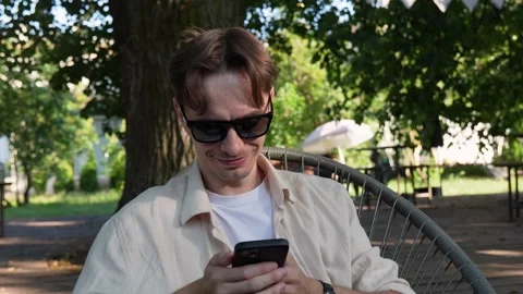 Young guy in sunglasses texting on a smartphone Stock Footage 280325770