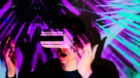 Young guy is surprised while using virtual reality glasses. Man gets experience Stock Footage 130176274
