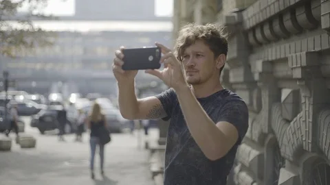 Young guy take a video with his cell phone in european city street Vídeos de archivo 95049582