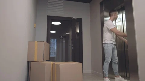 Young guy takes boxes with things that his girlfriend from elevator gives him Stock Footage 113751757