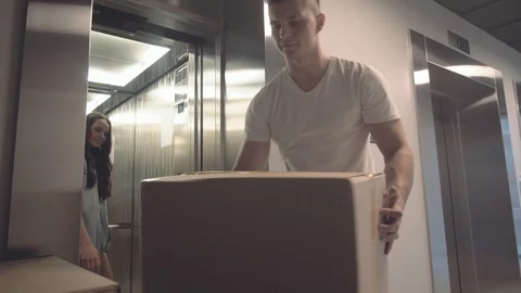 Young guy takes boxes with things from elevator that his girlfriend gives him Stock Footage 113751789