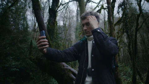 Young guy is taking selfies in forest with phone, Handsome photographer Stock Footage 147493119