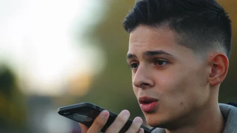 Young guy talking in voice chat on the phone on the street Видео 97409239