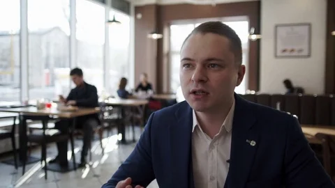 Young guy tells something at a table in a cafe Stock Footage 81821204