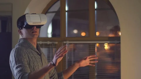 Young guy testing virtual reality in his living room in the evening Stock Footage 72285393