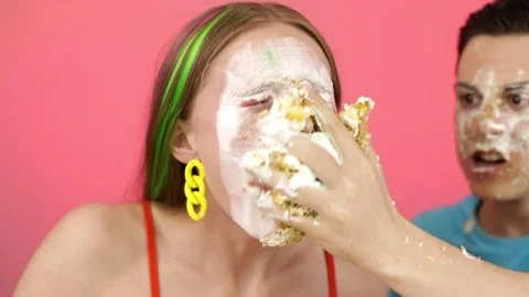 A young guy throws a cake at a girl. Stock Footage 166560864