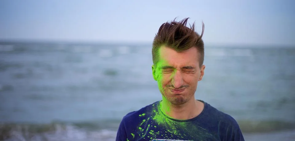 A young guy throws colour powder against the background of the sea Stock Photos