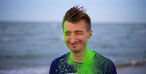 A young guy throws colour powder against the background of the sea Stock Photos