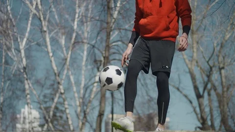 A young guy throws a soccer ball with his feet. Boy with a ball on the street. Stock Footage 114132831