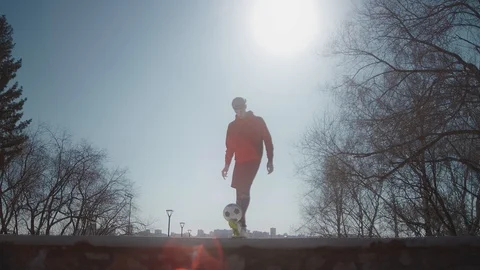 A young guy throws a soccer ball with his feet. Boy with a ball on the street. Stock Footage 114133105