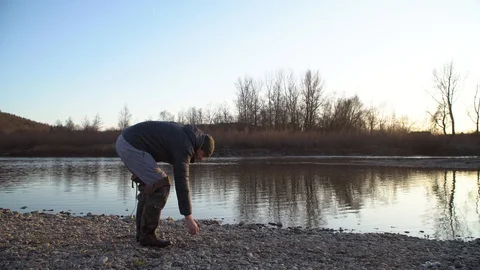 Young guy throws stones on the water.The rock jumps on the water Stock Footage 120698917