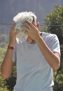 A young guy tilts his head down with moving hands on hairs  Stock Photos