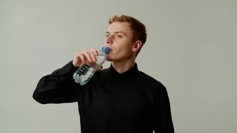 Young guy tired and drinking cold water. Businessman resting after long busy Stock Footage 256214850