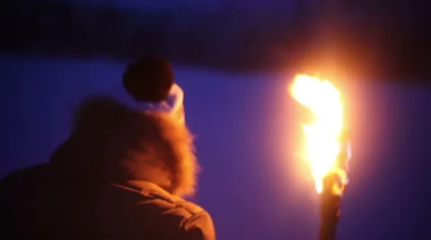 A young guy with the torch goes through the snow-covered field at night Stock Footage 64701890
