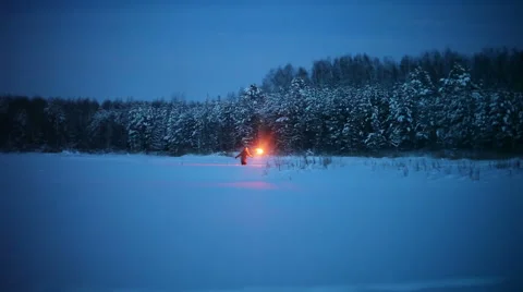 A young guy with the torch goes through the snow-covered field at night Stock Footage 64701903