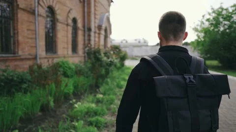 Young guy tourist with a backpack walking in the old town on a sunny day Stock Footage 133367131