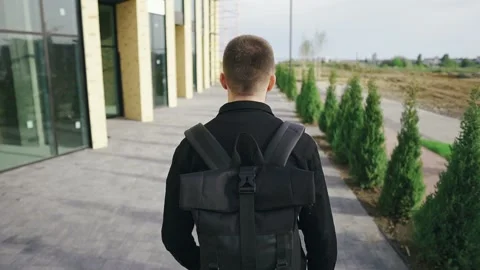 Young guy tourist with a backpack walking near a shopping center on a sunny day Stock Footage 134463727
