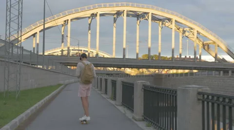Young guy in town on a skateboard with a tablet in hand in the summer Stock Footage 65371632