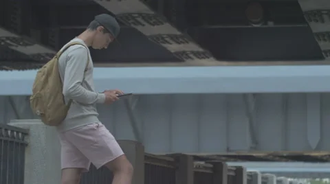 Young guy in town on a skateboard with a tablet in hand in the summer Stock Footage 65373478