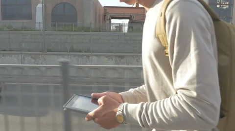 Young guy in town on a skateboard with a tablet in hand in the summer Video stock 65378393
