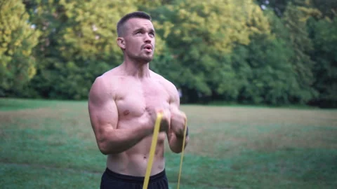 Young guy training in the park with an elastic band. Pull up exercise. Stock Footage 160165448