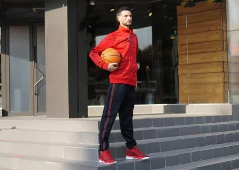 Young guy in training suit posing with basketball in front of store. 写真素材