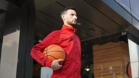 Young guy in training suit posing with basketball in front of store. Foto stock