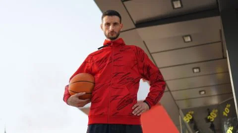 Young guy in training suit posing with basketball in front of store. Foto stock