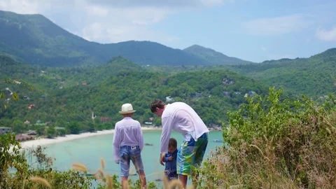A young guy with two children playing against the background of sea and 스톡 동영상 74739639