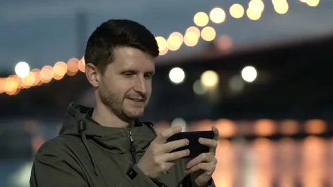 Young guy is typing a message on mobile phone and smiling. Close up looks good. Stock Footage 99433555